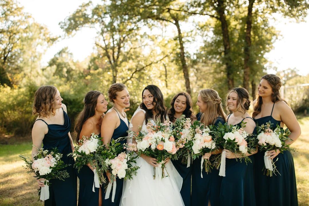 group of women standing next to each other holding bouquets
