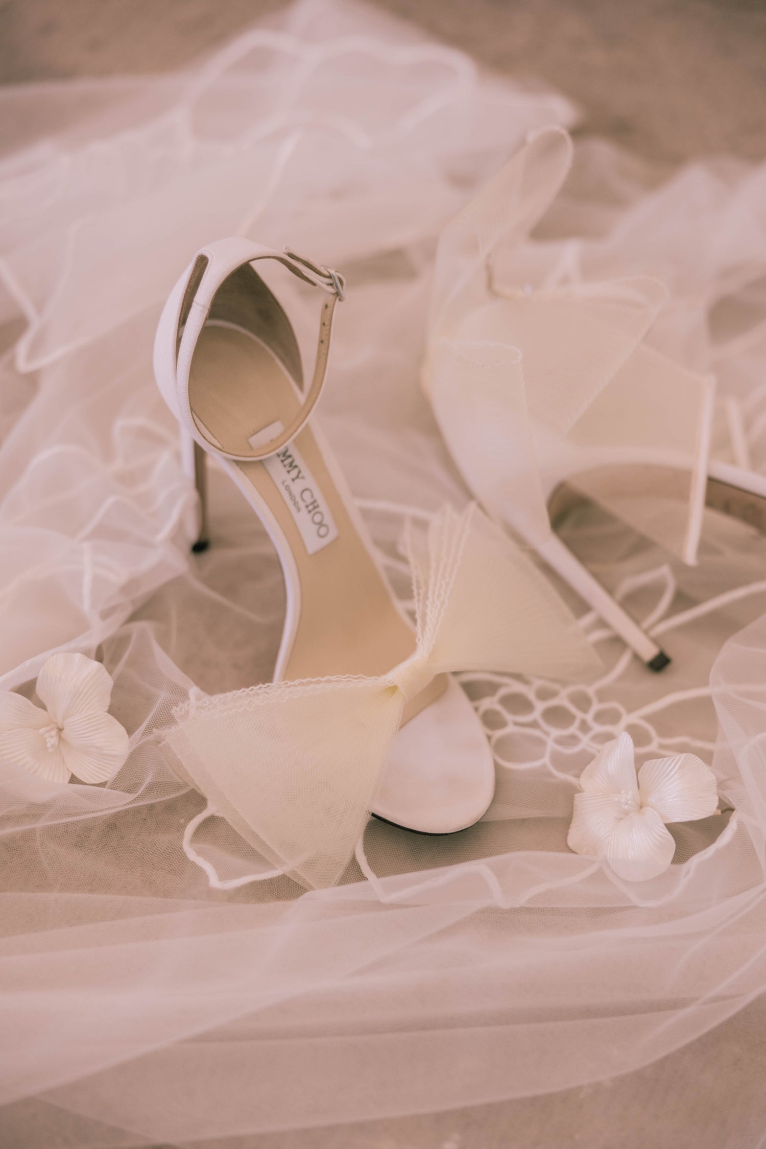A pair of white shoes and a veil on a bed