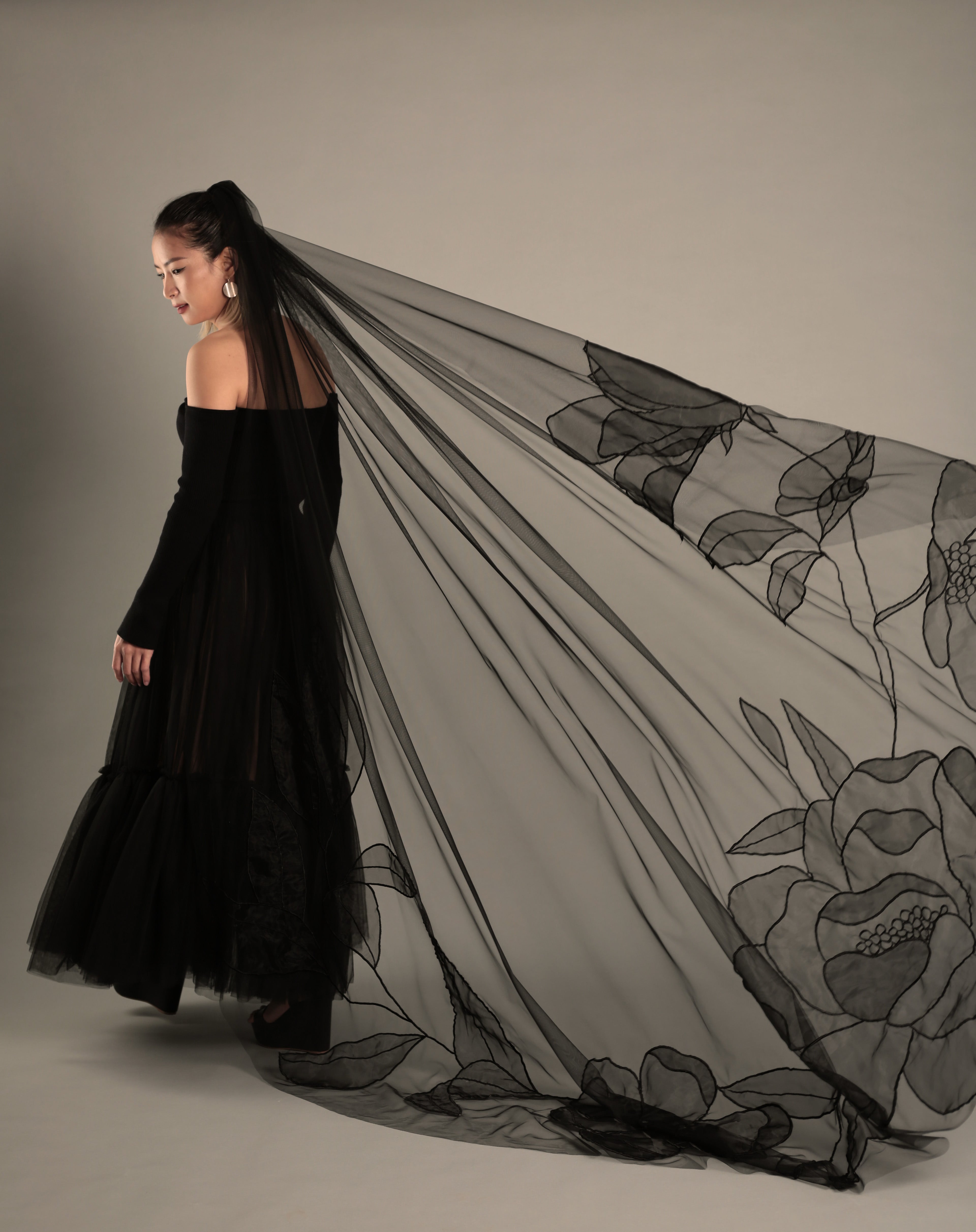 A bride wearing a stylish black wedding veil, highlighting the AUDREY design and its elegant drape.

