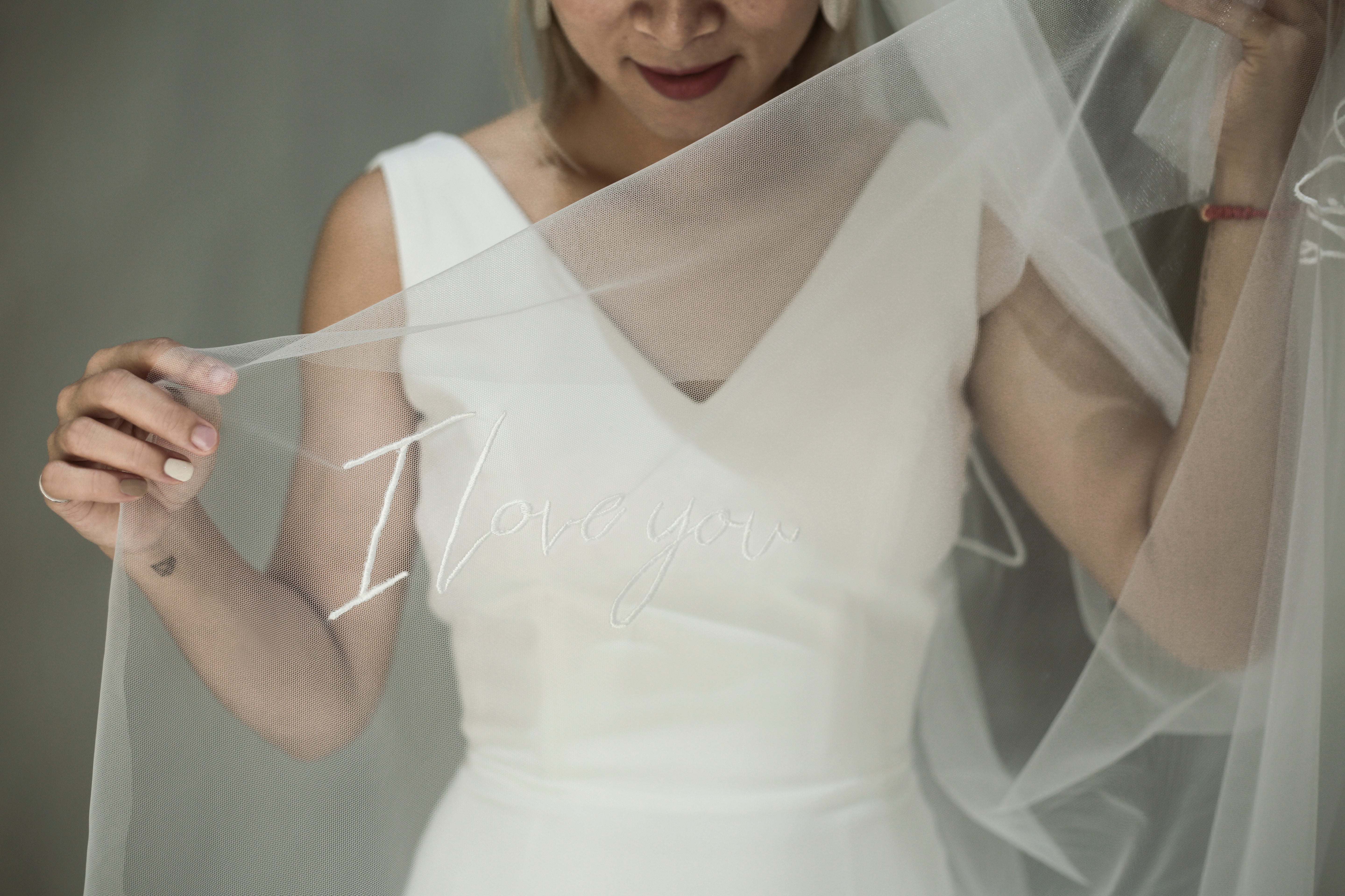 A bride wearing the ARIS embroidered veil, showing the elegant pattern and sheer fabric.


