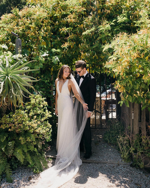 A botanical garden rustic warm and intimate wedding featuring a veil with mix of roses, cosmos, and calla lilies, embroidered onto delicate silk tulle, cathedral length
