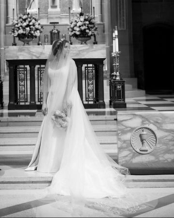 Bride wearing cathedral-length floral wedding veil with a blusher and floral crown in a traditional church wedding