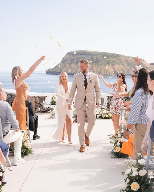 Joyful bride walking down the aisle with floral fingertip wedding veil oceanfront venue in Portugal