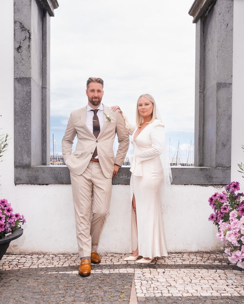 Confident modern bride and groom oceanfront venue in Portugal featuring a fingertip-length floral wedding veil