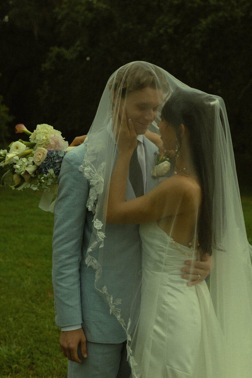Bride Mckhayla wearing a cathedral-length lace floral veil in a vintage bohemian garden theme wedding