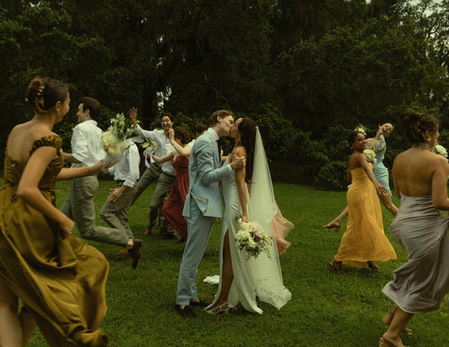 Bride Mckhayla wearing a cathedral-length lace floral veil in a vintage bohemian garden theme wedding kissing under an old giant tree