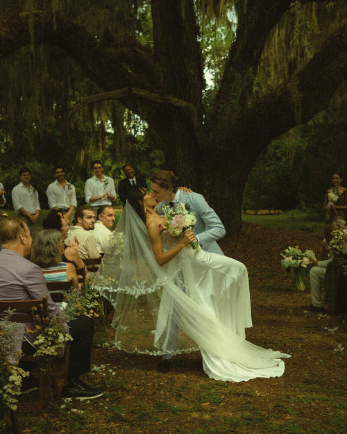 Bride Mckhayla wearing a cathedral-length lace floral veil in a vintage bohemian garden theme wedding under an old giant tree