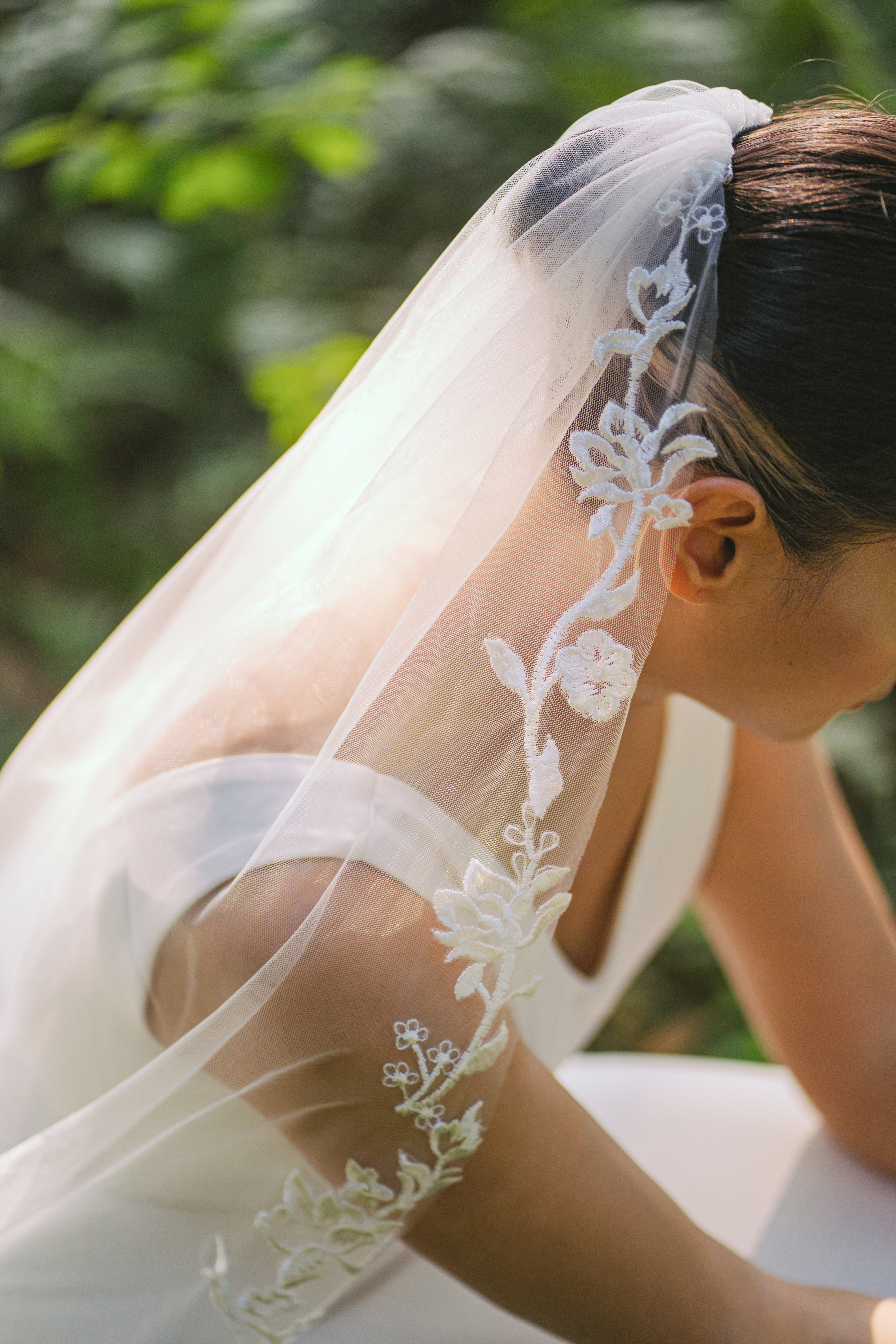 closeup shot ELA lace embroidery cathedral scallop-shaped wedding veil, bride walking in a sunny rain forest