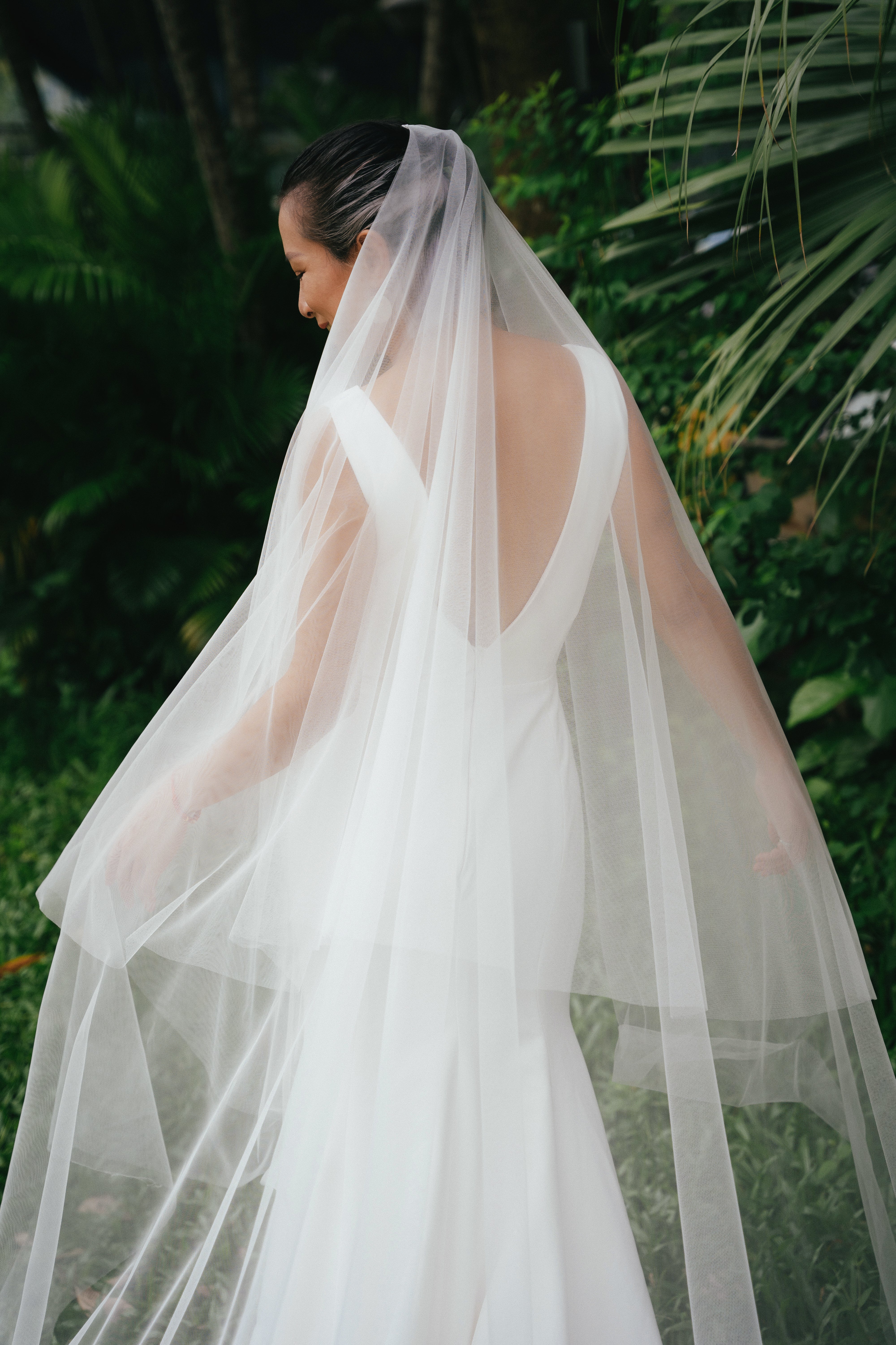 The floral lace hem of the JESI veil, highlighting the sheer organza and long, flowing royal cathedral train.