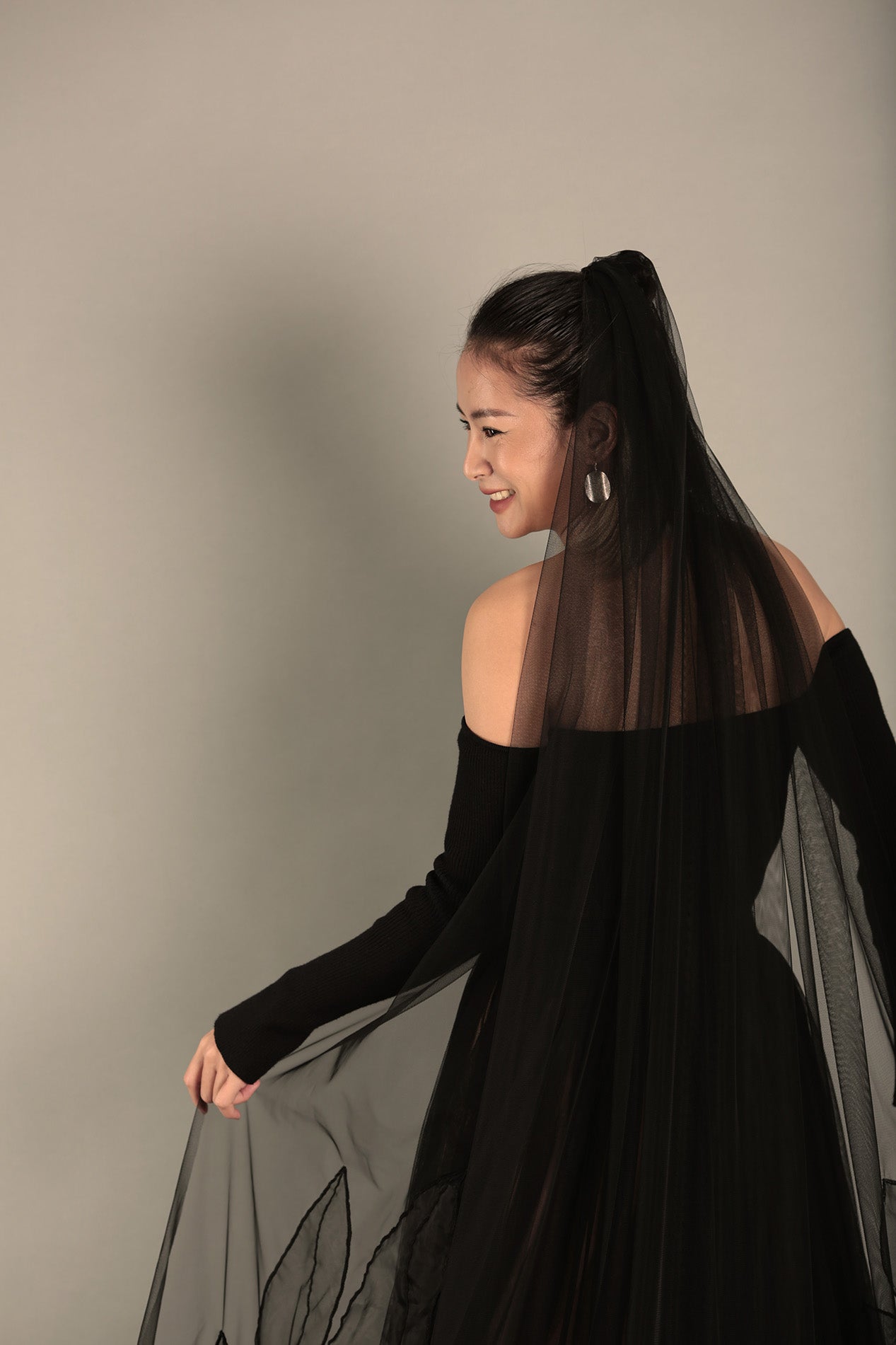 A bride with the AUDREY black veil, worn to show off its full, dramatic look.

